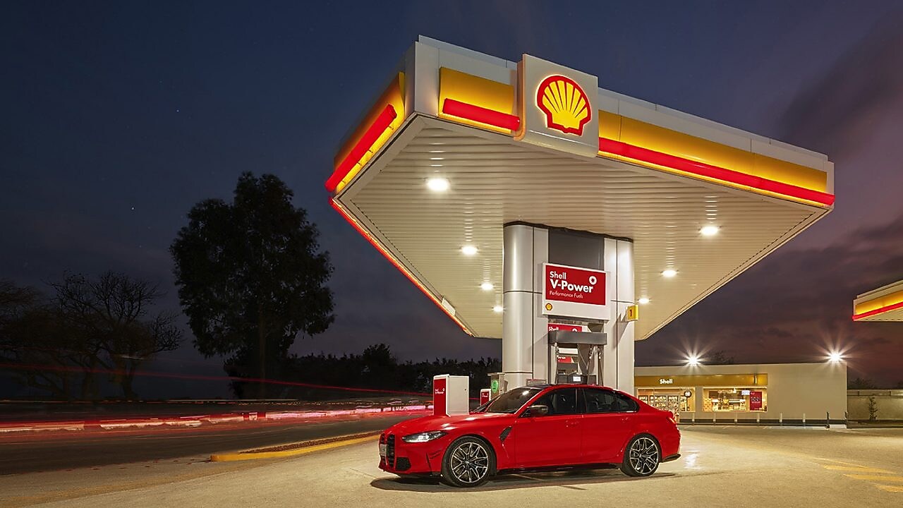 Coche rojo estacionado em estación de servicio de Shell a la noche
