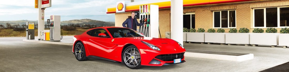Hombre blanco com su coche Ferrari rojo en una estación de servicio de Shell