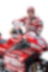 Andrea Dovizioso, hombre blanco con barba negra, en su uniforme de equipo Ducati, veste una gorra y posa con su moto
