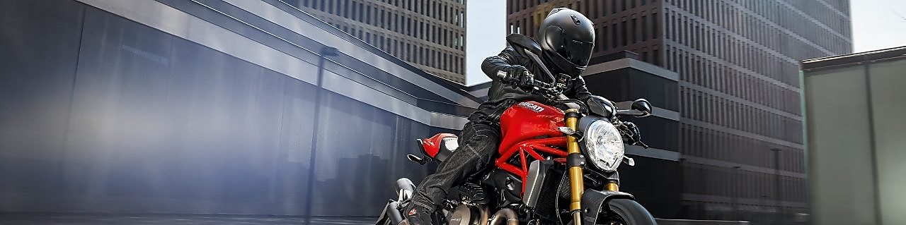 Motociclista con ropa negra y casco sobre motocicleta roja