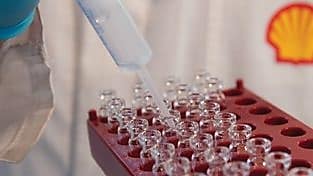 Mano con guante de laboratorio trabajando en viales con líquido transparente