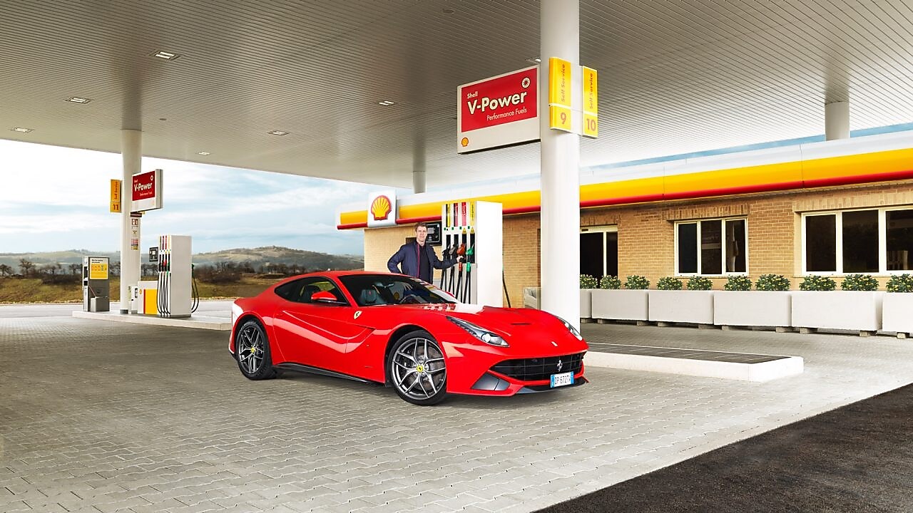 Hombre blanco com su coche Ferrari rojo en una estación de servicio de Shell