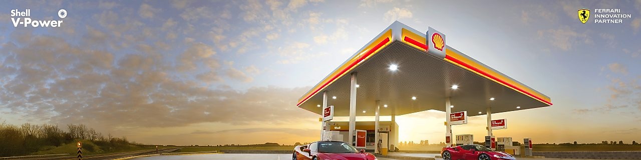 Coche rojo estacionado em estación de servicio de Shell a la noche