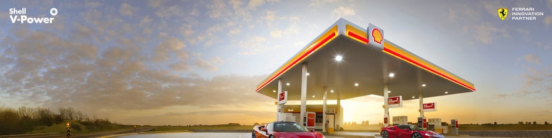 Coche rojo estacionado em estación de servicio de Shell a la noche